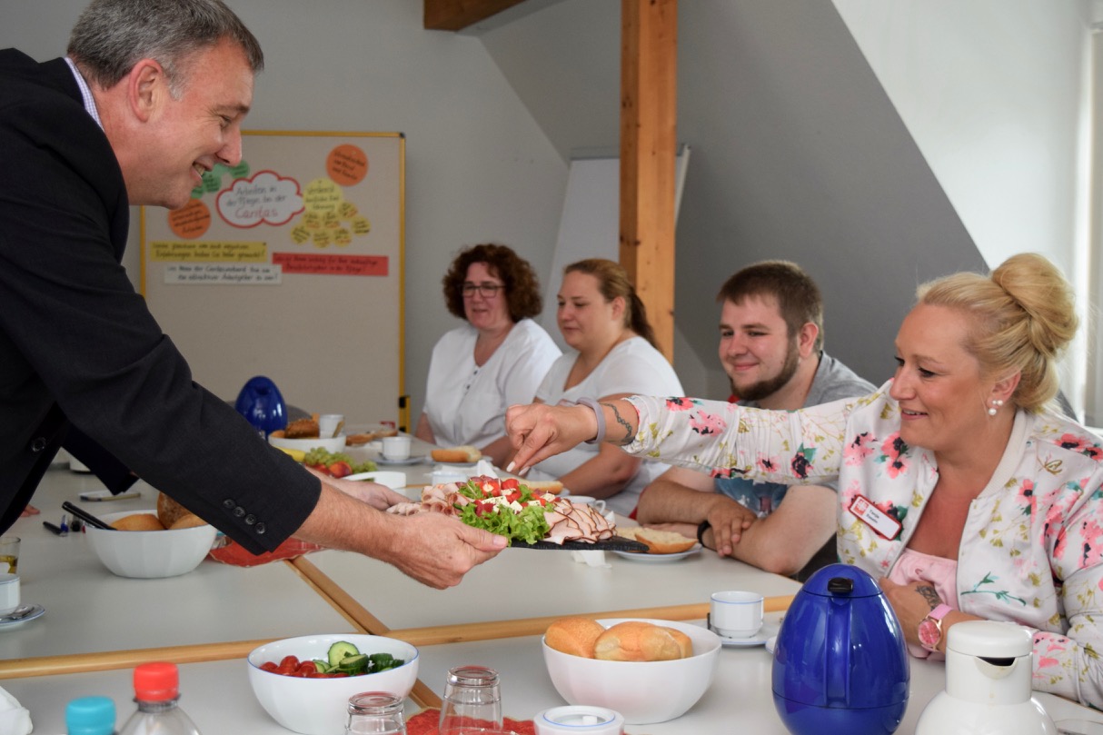 Caritas-Vorstandssprecher Ralf Regenhardt bietet beim Dankeschön-Frühstück die Aufschnittplatte an.