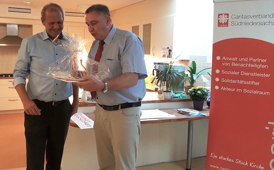 Caritasvorstand Ralf Regenhardt (r.) übereicht ein Stück Kuchen an den CDU-Bundestagsabgeordneten Fritz Güntzler.