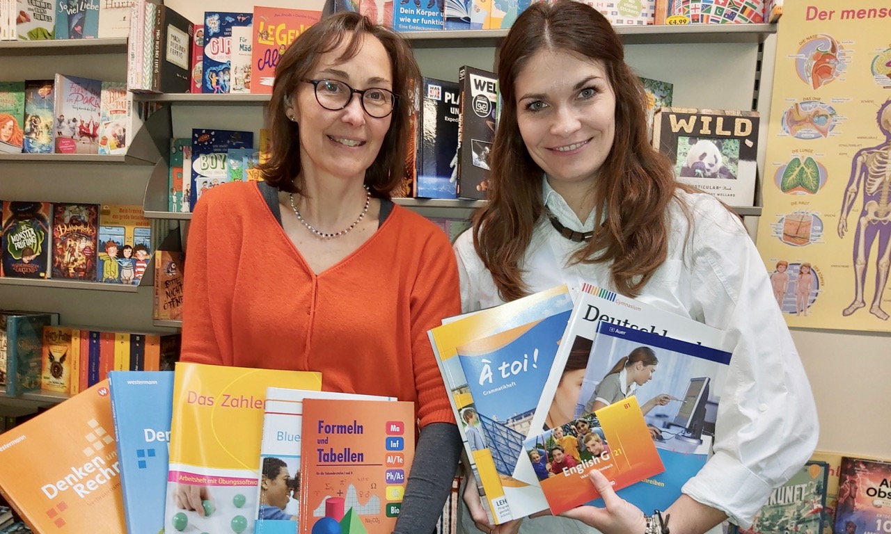 Die Caritas-Beraterinnen Maria Weiss (l.) und Isabel Lubojanski zeigen Schulbücher in der Duderstädter Buchhandlung Mecke. | Foto: Caritas Südniedersachsen